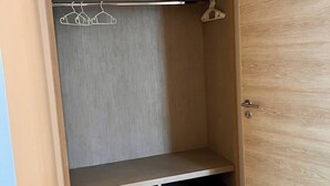 A walk-in closet with wooden flooring, a grey door, and a hanging rod. - Breezy Condo in Aonang (Krabi)