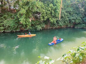 Une rivière paisible où l’on peut faire du kayak et où une personne est sur un radeau.