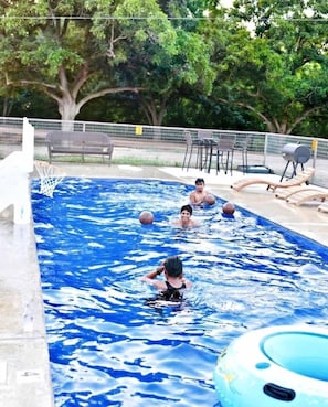 A swimming pool with a basketball hoop, surrounded by a fence and trees. - Discover Glamping at its Best in this Lovely Safari Tent Rental in the Heart of Texas (Cibolo)