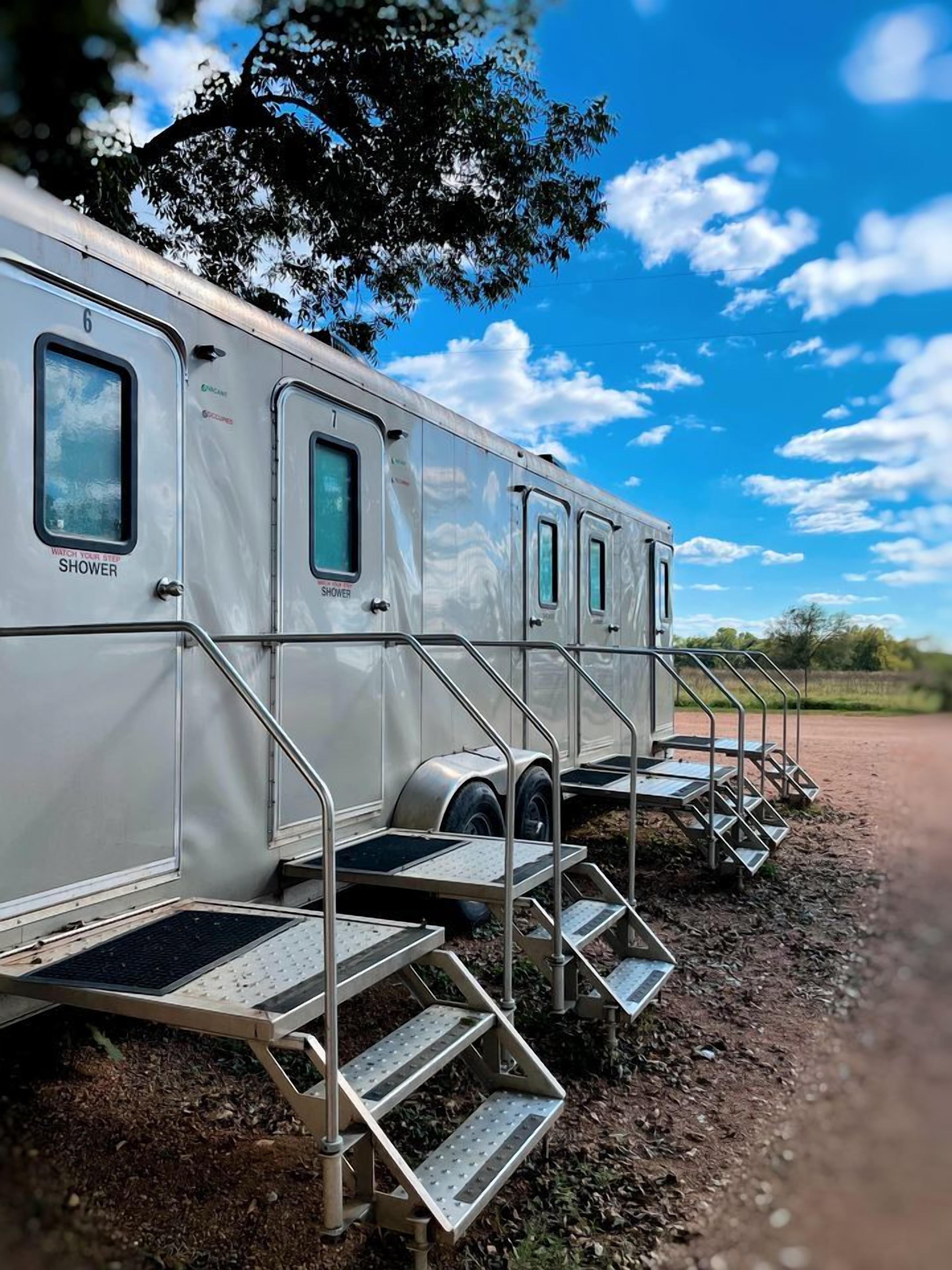 A row of RVs with external shower facilities and metal stairs leading to the entrance.