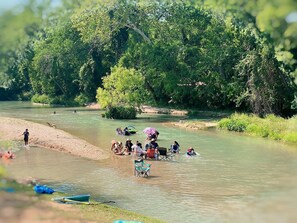 Ein Fluss mit Menschen, die sich verschiedenen Aktivitäten widmen, umgeben von viel Grün.