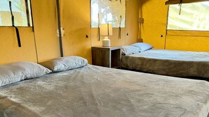 Une chambre avec deux lits, une table de chevet avec une lampe et une fenêtre donnant sur un beau paysage.