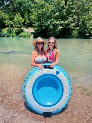 Deux personnes tenant un matelas gonflable bleu sur la rive d’une rivière.