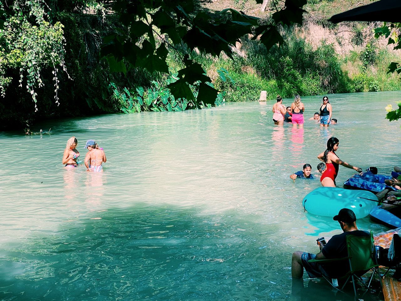 Un grupo de personas en un entorno acuático natural, rodeado de árboles y follaje.