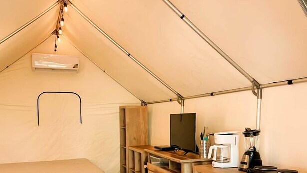 A tent with two beds, a kitchenette, and a small table. - Fantastic Glamping Getaway near Kingsbury, Texas: Beautiful Fully-Equipped Safari Tent on the San Marcos River (Kingsbury)