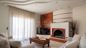 A living room with a fireplace, sofa, coffee table, and TV. - Casa di Vasia (Gennadi)