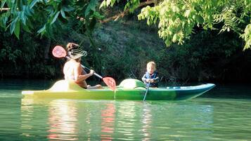 Two people kayaking on a calm river surrounded by greenery.