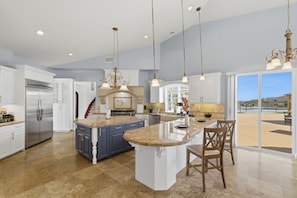 A spacious kitchen with a large island, stainless steel appliances, and a view to the outside.