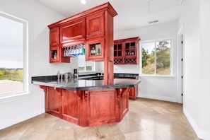 A kitchen with a central island, wooden cabinets, and a view of the outdoors.