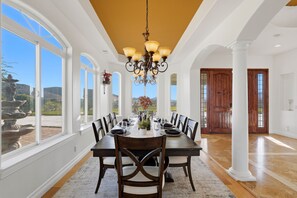 A dining room with a large table set for six, white columns, and a view of the outdoors.