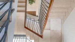 Ein modernes Interieur mit einer Wendeltreppe, Marmorböden und einer zentral platzierten Pflanze.