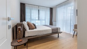 Ein modernes Schlafzimmer mit einem Bett, einem Nachttisch und einem Sessel.