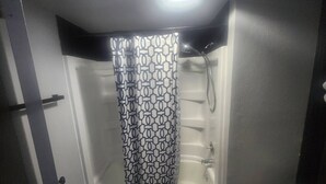 Un baño con cortina de ducha, bañera y retrete.