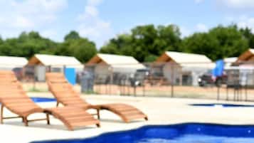 Una piscina con sillas de descanso y un flotador inflable rosa.