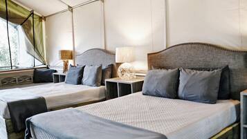 A room with two beds, each with a headboard, bedside tables, and lamps.