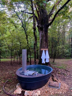 A hot tub in a forest setting with a wooden platform and towels hanging on a tree. - Glamping Tiny House Situated in the Tennesse Woods for a Tranquil Escape near Chattanooga (Signal Mountain)