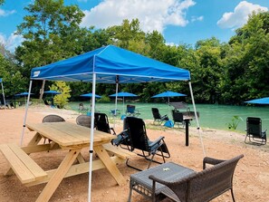 A picnic setup with a table, chairs, and a blue canopy.