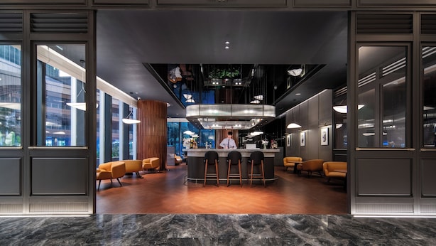 Un bar moderno con mostrador central, taburetes y zonas de estar.