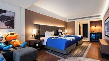 Una habitación de hotel con cama, escritorio, sillón, sofá y televisor.