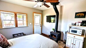 A bedroom with a bed, a ceiling fan, a fireplace, a television, and a microwave. - Santa Ysabel Lakeview Glamping: Your Secluded Nature Escape (Santa Ysabel)