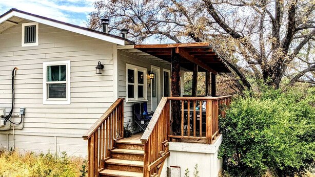 A two-story house with a wooden staircase leading to a porch. - Santa Ysabel Lakeview Glamping: Your Secluded Nature Escape (Santa Ysabel)