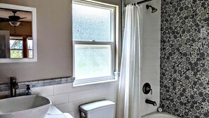 A bathroom with a white sink, toilet, and bathtub. There is a window above the sink and a shower curtain. - Santa Ysabel Lakeview Glamping: Your Secluded Nature Escape (Santa Ysabel)