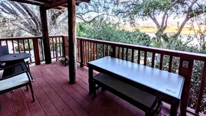 A covered outdoor area with a wooden bench and chairs, surrounded by a wooden railing. - Santa Ysabel Lakeview Glamping: Your Secluded Nature Escape (Santa Ysabel)