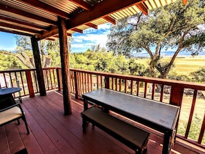 Eine Holzterrasse mit Tisch und Bank, mit Blick auf eine reizvolle Landschaft.