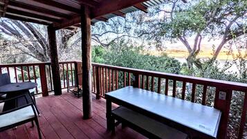 A covered outdoor area with a wooden bench and chairs, surrounded by a wooden railing.