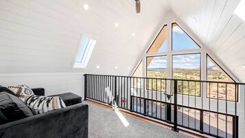 A modern loft bedroom with a large skylight, a ceiling fan, and a view of a desert landscape.