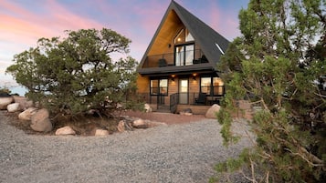 A modern house with a triangular roof, large windows, and a gravel driveway.