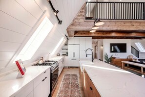 A modern kitchen with skylights, a dining area, and a living space with a TV. - Experience Pure Glamping on this A-frame Placed in the Middle of the Desert in Wayne County, Utah (Wayne County)