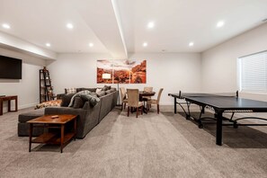 Ein Wohnzimmer mit einer Couch, einem Couchtisch, einem Fernseher und einem Tischtennistisch.
