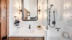 A modern bathroom with a white sink, a large mirror, a glass-enclosed shower, and wooden cabinetry. - Experience Pure Glamping on this A-frame Placed in the Middle of the Desert in Wayne County, Utah (Wayne County)
