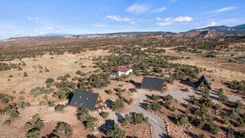 A remote, arid landscape with sparse vegetation and a few isolated buildings.