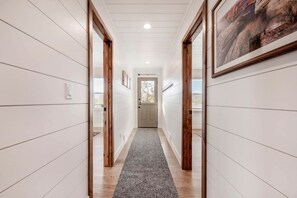 A hallway with white paneling, wooden doors, a gray carpet, and a framed picture on the wall. - Experience Pure Glamping on this A-frame Placed in the Middle of the Desert in Wayne County, Utah (Wayne County)