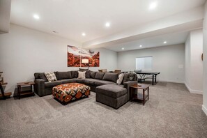 Una sala de estar con un sofá modular, un reposapiés y un cuadro en la pared.
