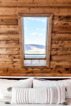 A wooden cabin interior with a window overlooking a mountainous landscape. - Experience Pure Glamping on this A-frame Placed in the Middle of the Desert in Wayne County, Utah (Wayne County)