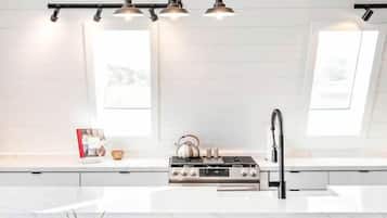 Een moderne keuken met een centraal eiland, hanglampen en uitzicht op de omgeving.