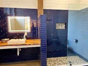 A bathroom with a sink, mirror, and shower area. - Peaceful Cabin Stay with Fire Pit, Sauna & Mountain Adventure in Zirconia, North Carolina (Zirconia)