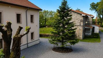 A courtyard with a paved walkway, a small tree, and a building with a tiled roof.