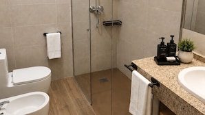 A modern bathroom with a glass-enclosed shower, a toilet, a bidet, and a sink with a countertop. - Hospederia La Serrana (Piornal)