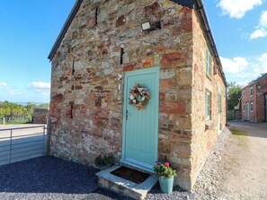 A stone building with a green door, a small porch, and a wreath.
