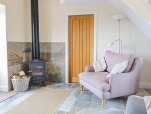Una sala de estar con chimenea de piedra, puerta de madera, un sofá y una lámpara.
