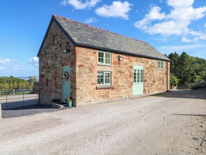 A stone building with a sloped roof, two windows, and a door.