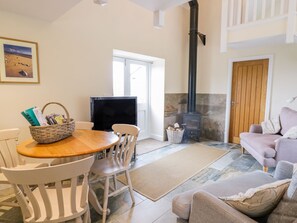 Una sala de estar acogedora con chimenea, televisión, mesa de comedor con sillas, sofá y una puerta.
