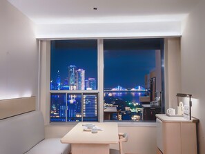 A room with a large window overlooking a cityscape at night, a small table with teapots, and a cabinet with a lamp. - JI Wuhan Jianghan Road Pedestrian Street (Wuhan)