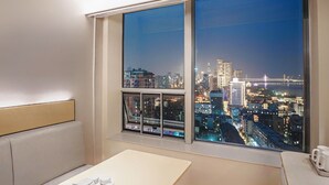 A room with a large window offering a city view at night, a small table with cups, and a cushioned bench. - JI Wuhan Jianghan Road Pedestrian Street (Wuhan)