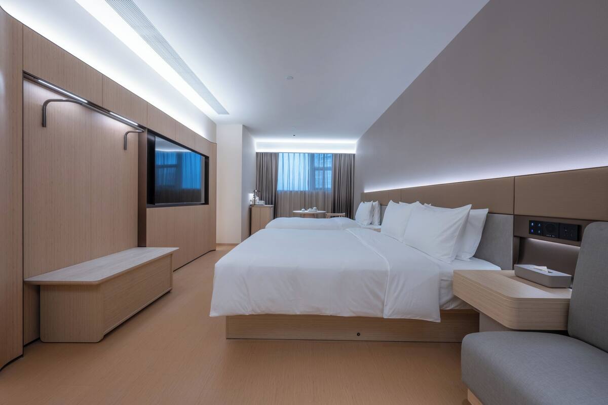 Habitación de hotel moderna con una cama grande, mesitas de noche, televisión y vistas a la ciudad.