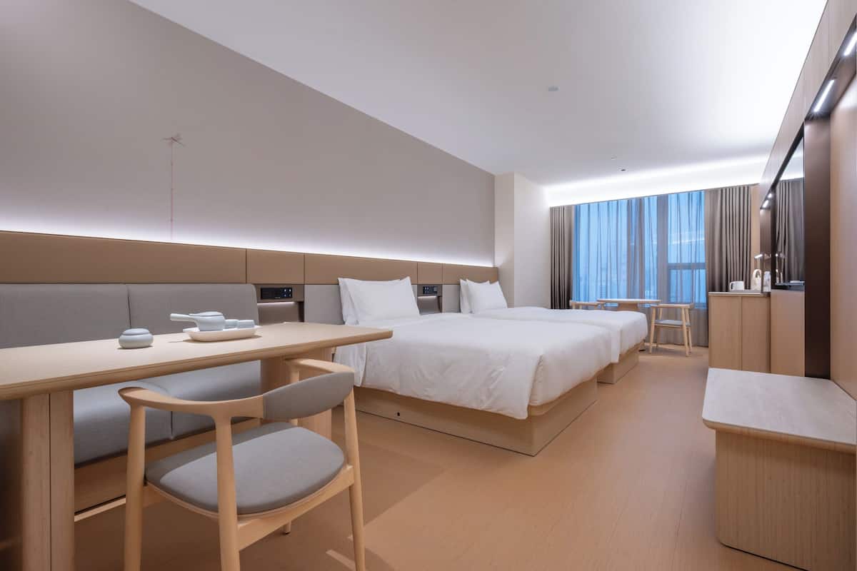 Una habitación de hotel moderna con una cama grande, un escritorio, una silla y una mesita.